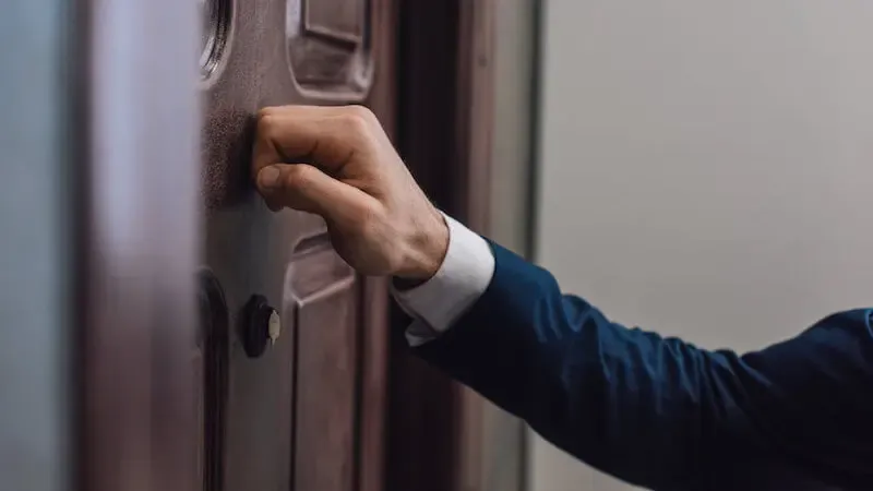 Behold, I stand at the door and knock showing a man knocking at the door
