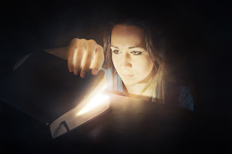 God's will is in the scriptures showing a woman looking at a glowing Bible