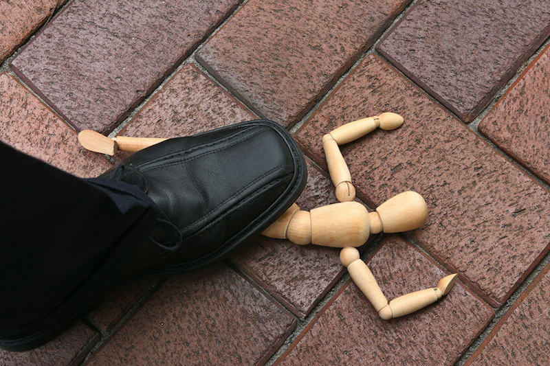 The defeat of satan image showing an image of a wooden man smashed under the soles of a man's shoes