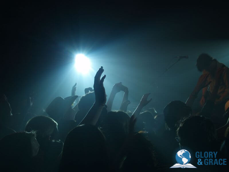 Fellowship with God's presence image showing a worship service with hands lifted up
