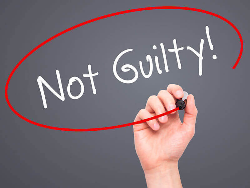 Justification by grace with a writing on a black board stating "not guilty"