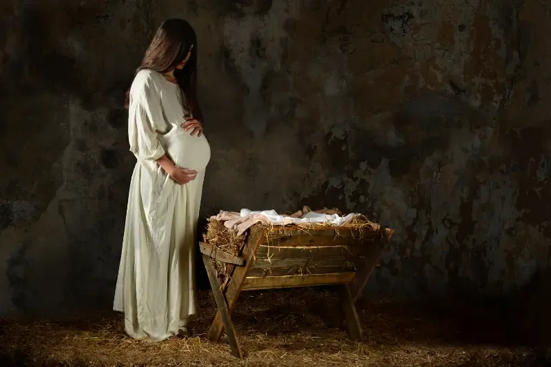 Mary the mother of Jesus showing a pregnant woman by a crib
