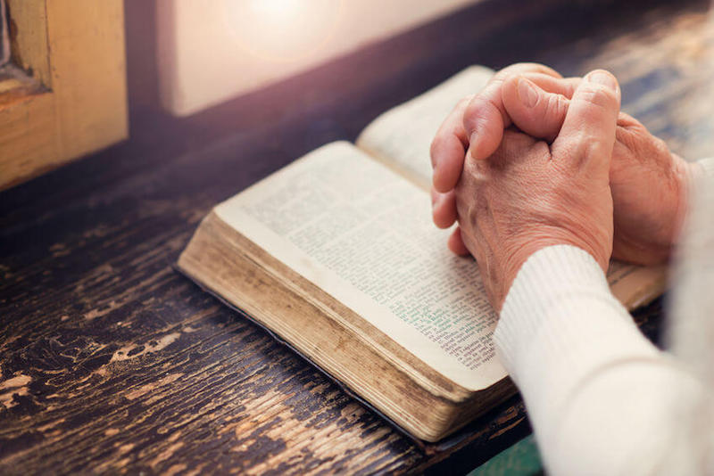 Understanding the trinity image showing a man's hand on a bible seeking to understand