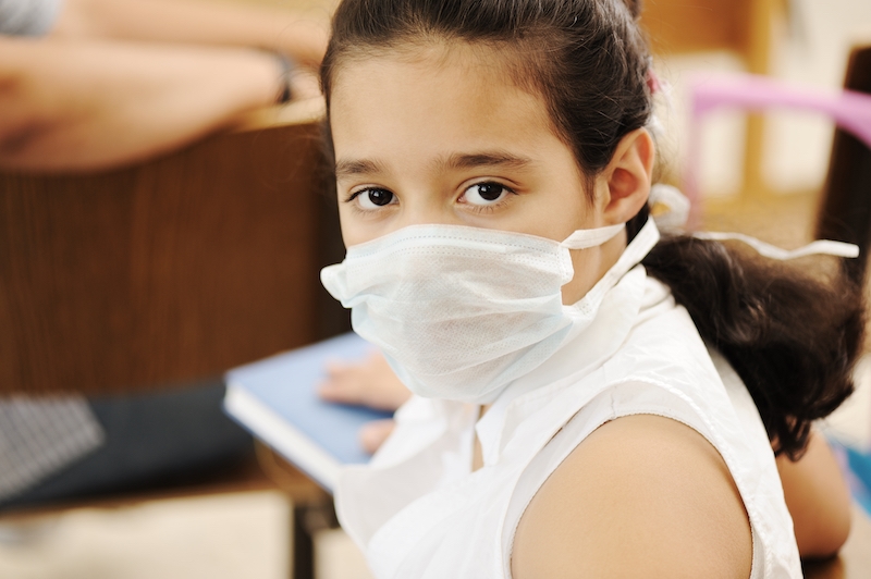 Schoolgirl with medicine mask on face, in classroom, against: virus, ill, epidemic, plague, flu