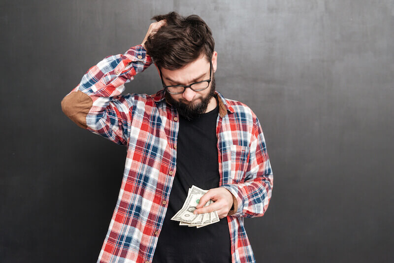 spiritual purpose of money showing someone scratching his heed with money in his hands
