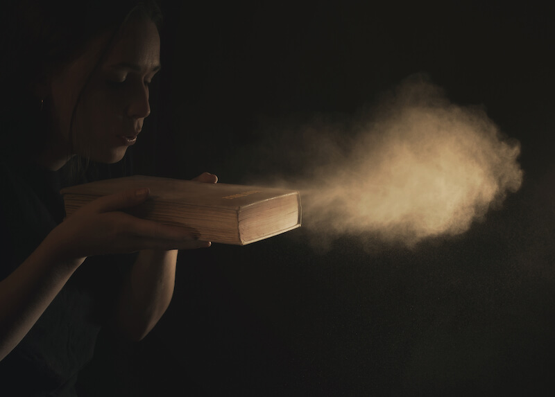 The human spirit as the wind of change showing a woman blowing dust off her bible