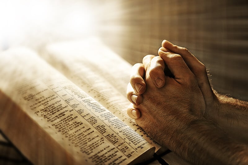 devotional life showing a man praying with his bible