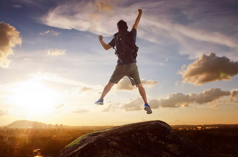 Faith removes mountains showing a man jumping at the mountain peak