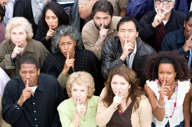 Silence showing many people in a group with their fingers on their mouths